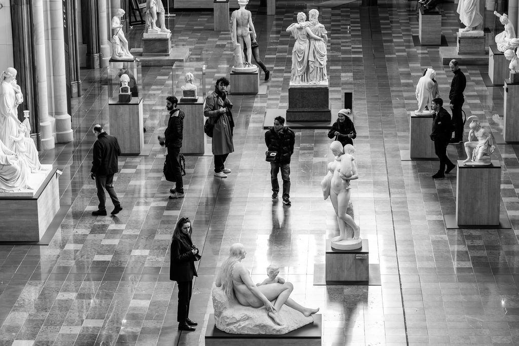 Besucher in einem Museum zwischen Skulpturen und Kunstwerken